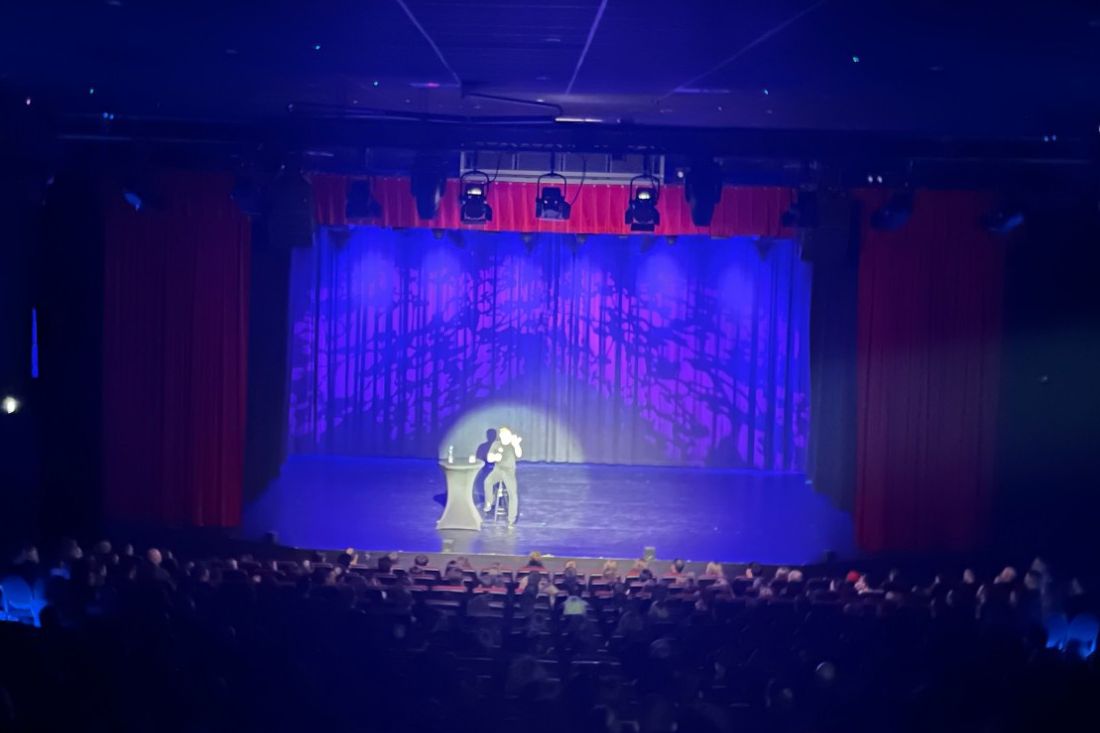 Daniel Sloss na scenie w świetle punktowym, widownia w pełnej sali